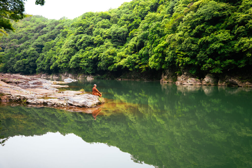 Monk in lotus position at a river in Kyoto, Japan